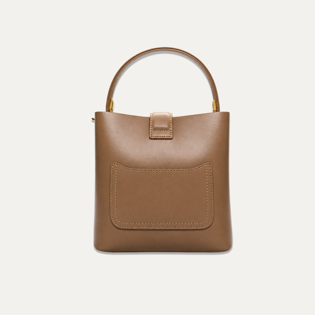 A structured tan leather handbag with a top handle, a front pocket, and gold-tone hardware, shown against a plain off-white background.