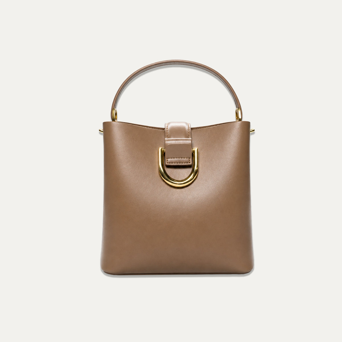 A structured brown leather handbag with a top handle, a gold-tone D-ring detail, and a matching leather strap, shown against a plain off-white background.