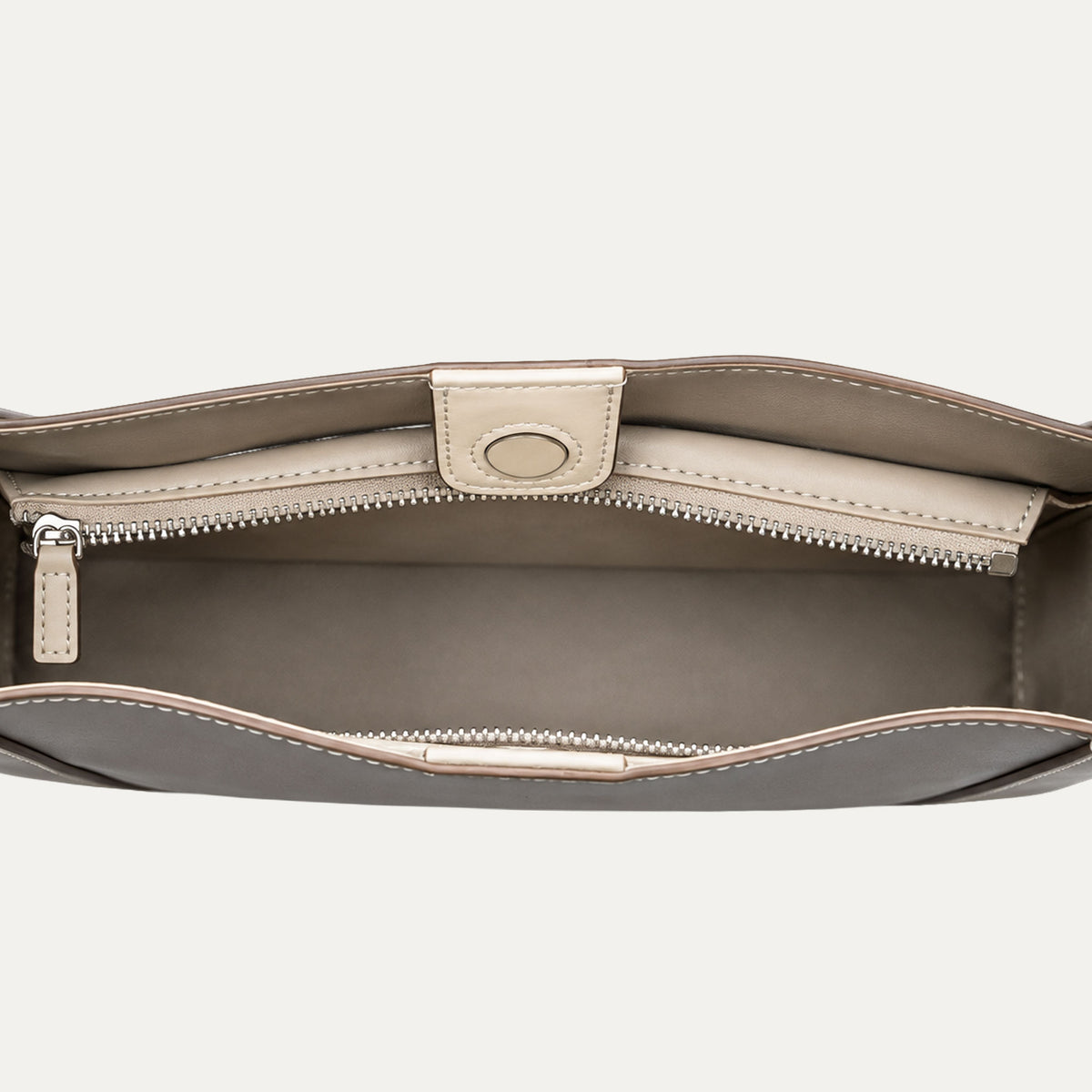 Close-up of the interior of a structured handbag, showing a zippered compartment with a taupe leather insert and a taupe-brown exterior.