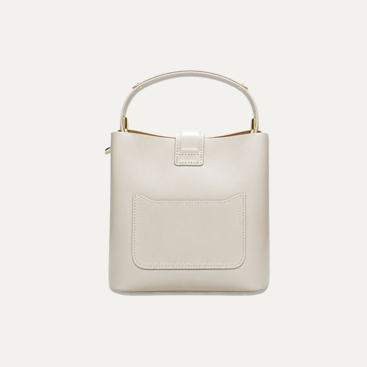 A structured cream-colored leather handbag with a top handle, gold-tone hardware, and a front slip pocket, shown against a solid off-white background.