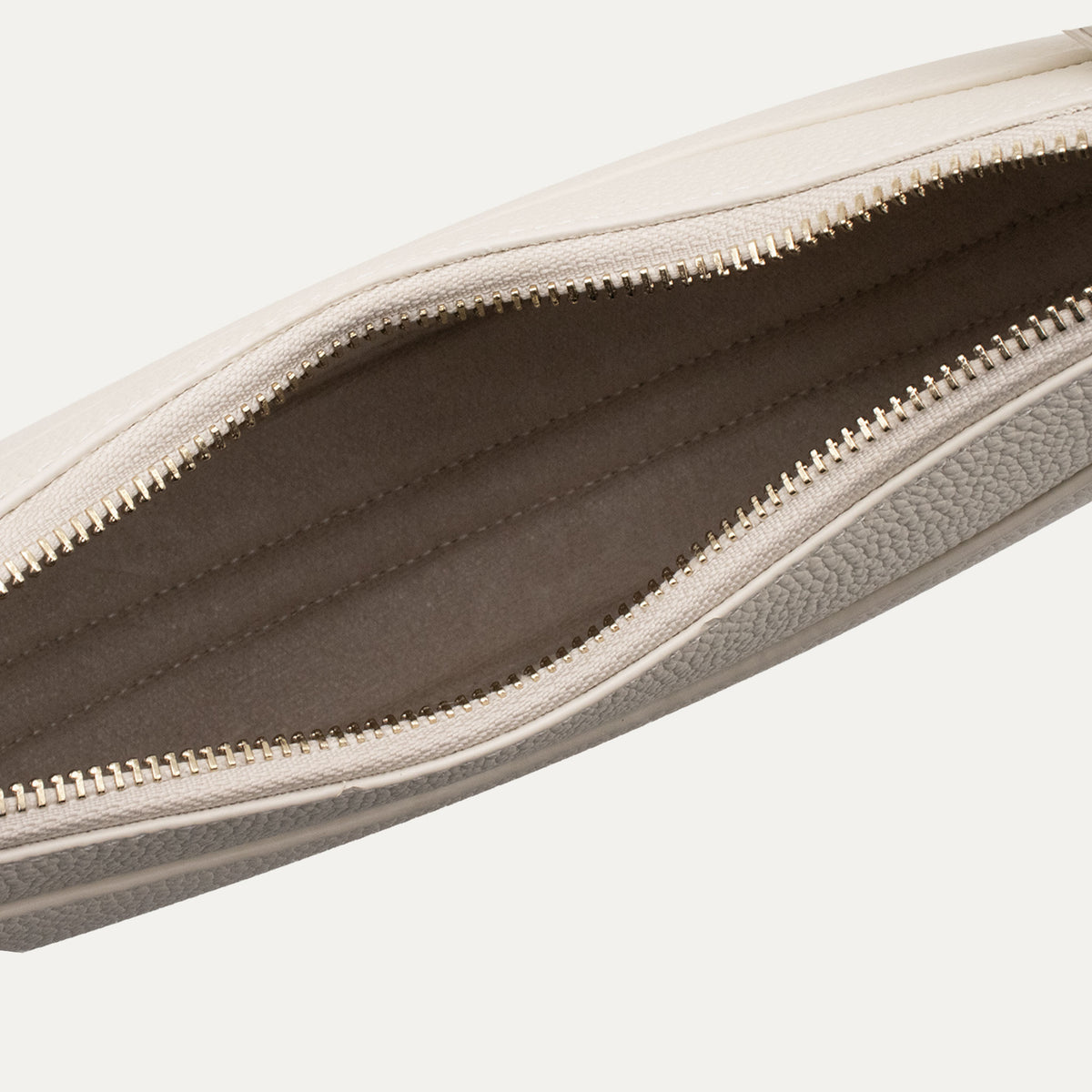 Close-up of a off-white leather zippered bag with a textured pebbled exterior and a smooth lining, shown open against a light off-white background.