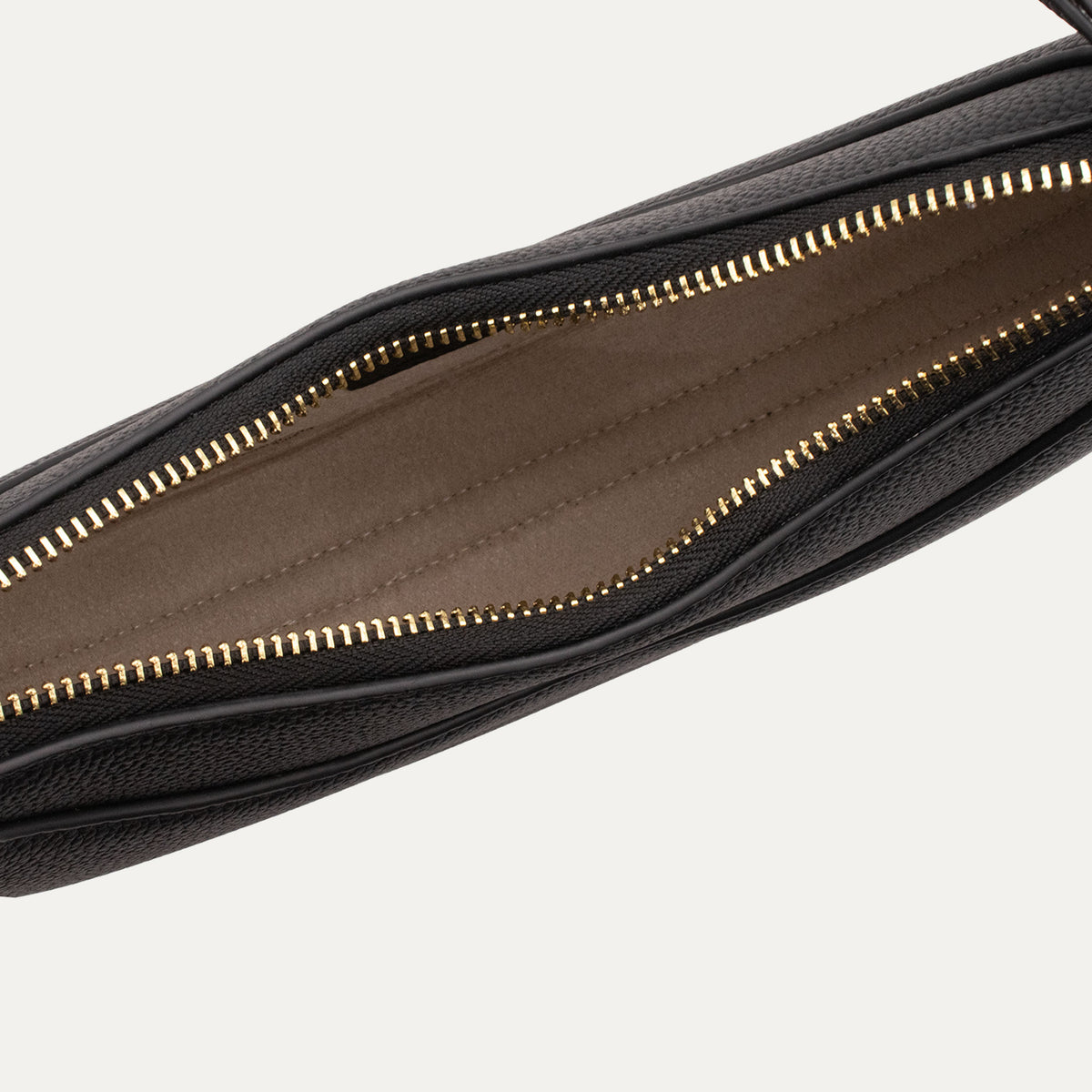 Close-up of a black pebbled leather bag, revealing a brown interior lining and gold-tone zipper teeth.
