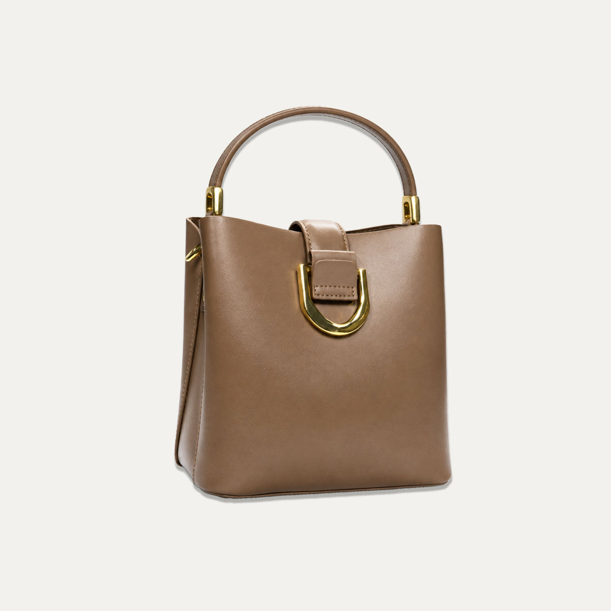 A structured brown leather handbag with a top handle, gold-tone hardware, and a prominent D-ring detail on the front, set against a plain off-white background.