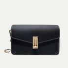 A black textured leather crossbody bag with white contrast stitching and a gold-tone turn-lock clasp, shown against a light off-white background.