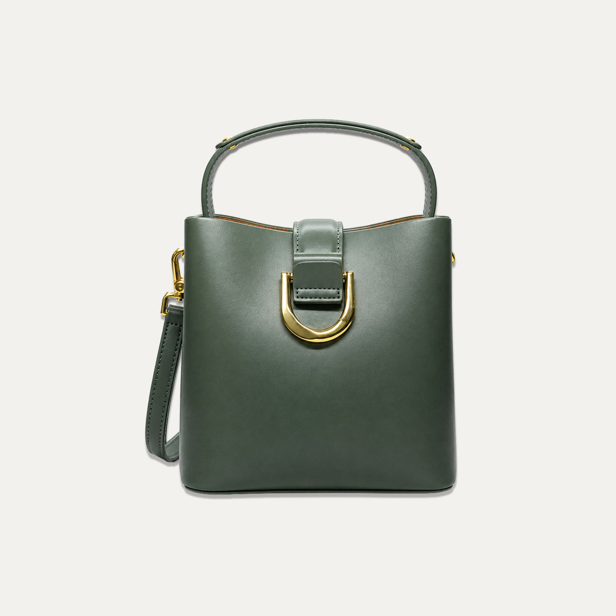 A structured sage green leather handbag with a top handle, a detachable shoulder strap, and a prominent gold-tone U-shaped hardware detail on the front, set against a solid off-white background.