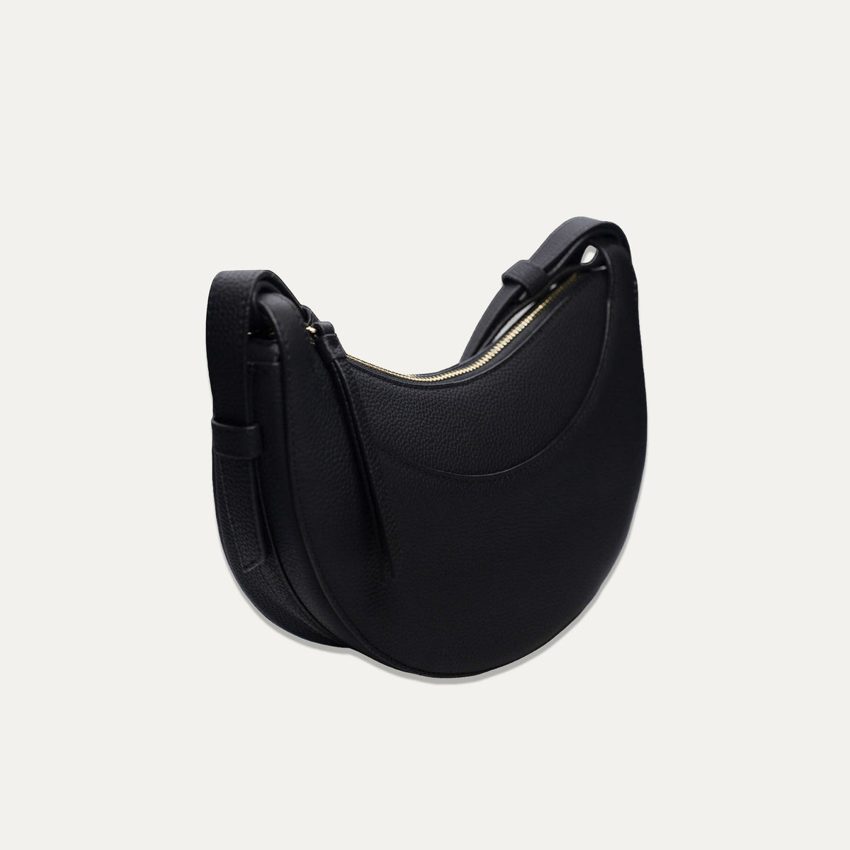 A black crescent-shaped leather shoulder bag with a curved top and a adjustable shoulder strap, shown on a light off-white background.