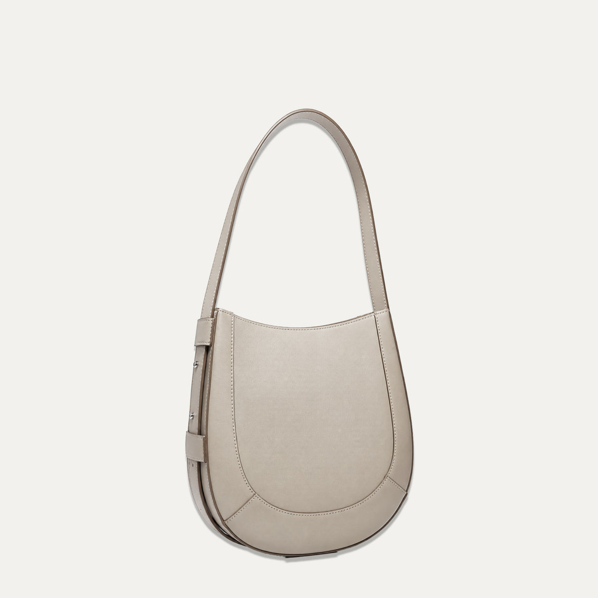 A taupe leather crescent-shaped shoulder bag with a single strap, shown against a solid off-white background.