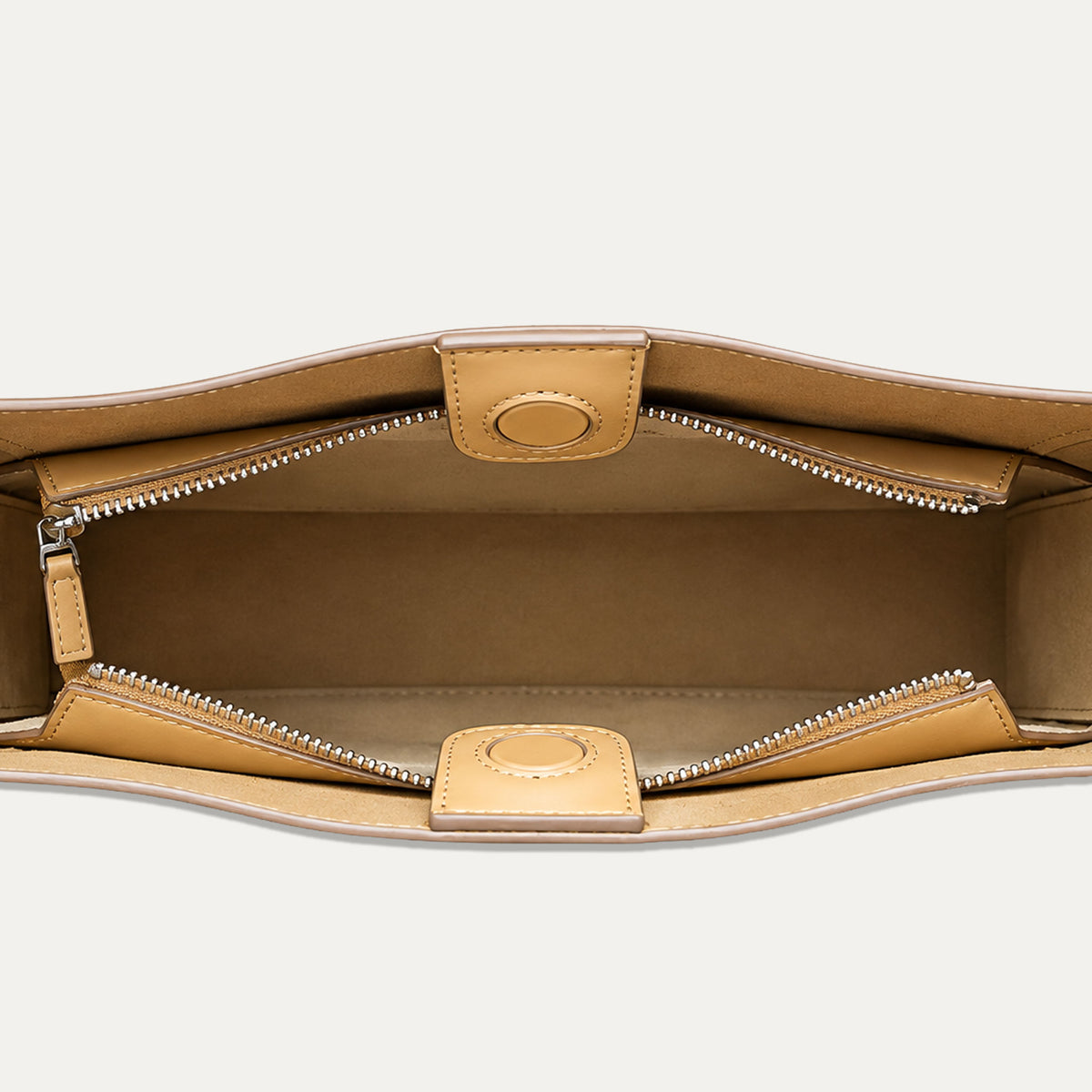 Close-up top-down view of a tan leather handbag interior with two silver zipper compartments and matching leather tab closures on a light gray background.