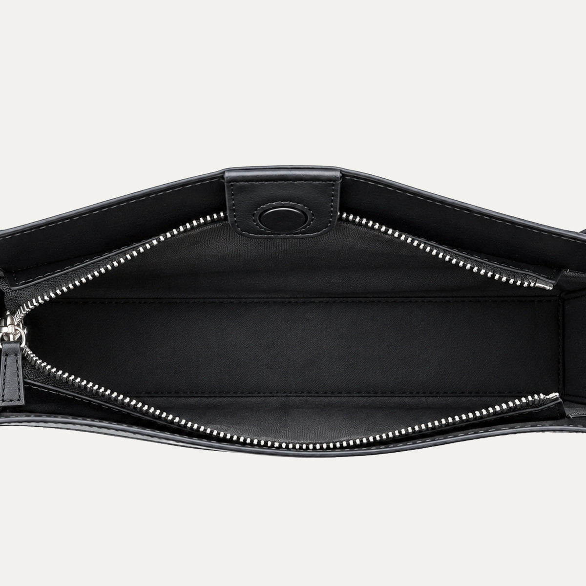 Close-up of the interior of a black leather bag, showing a zippered compartment with silver-tone zipper teeth and a black fabric lining.
